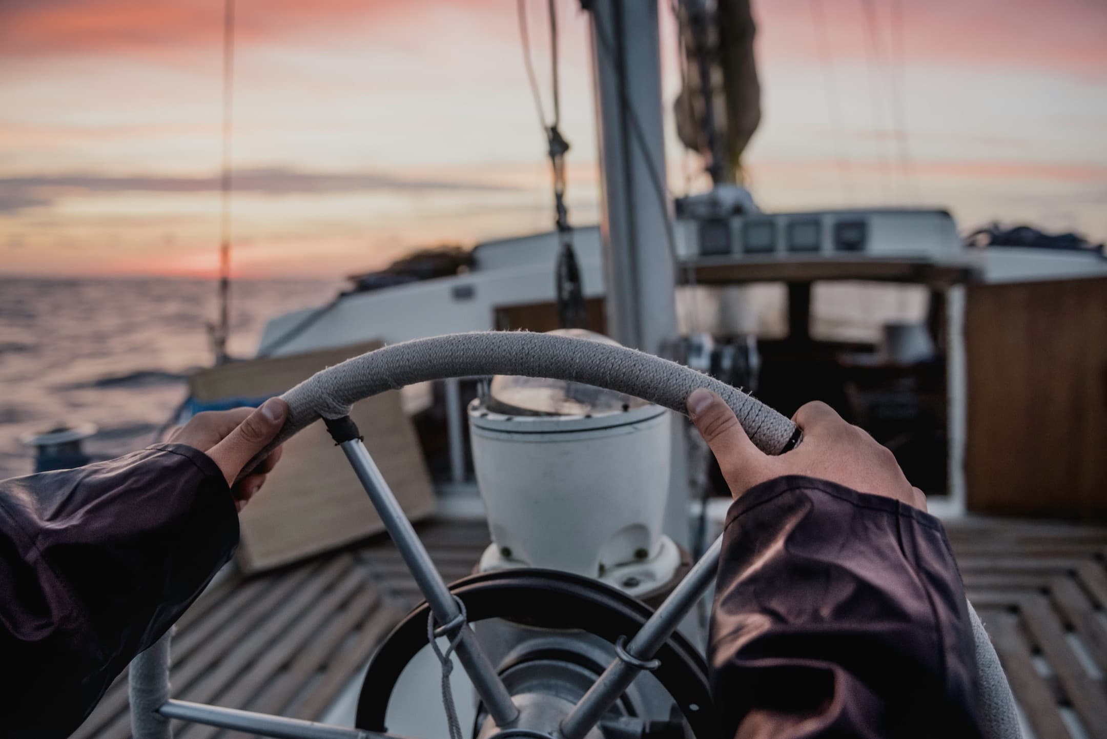 Manos en el timón de un velero al atardecer