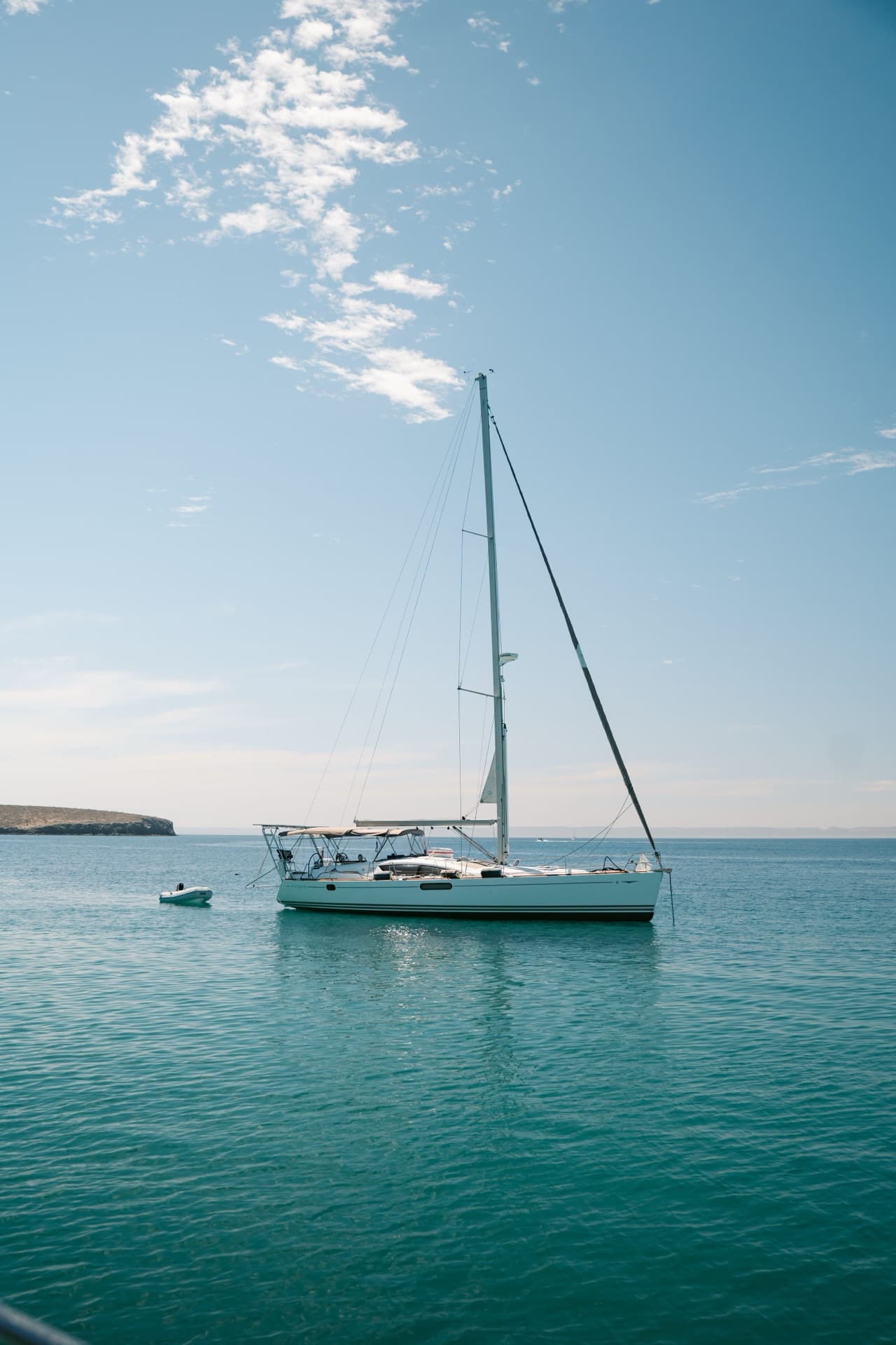 Velero blanco fondeado en agua verde azulada