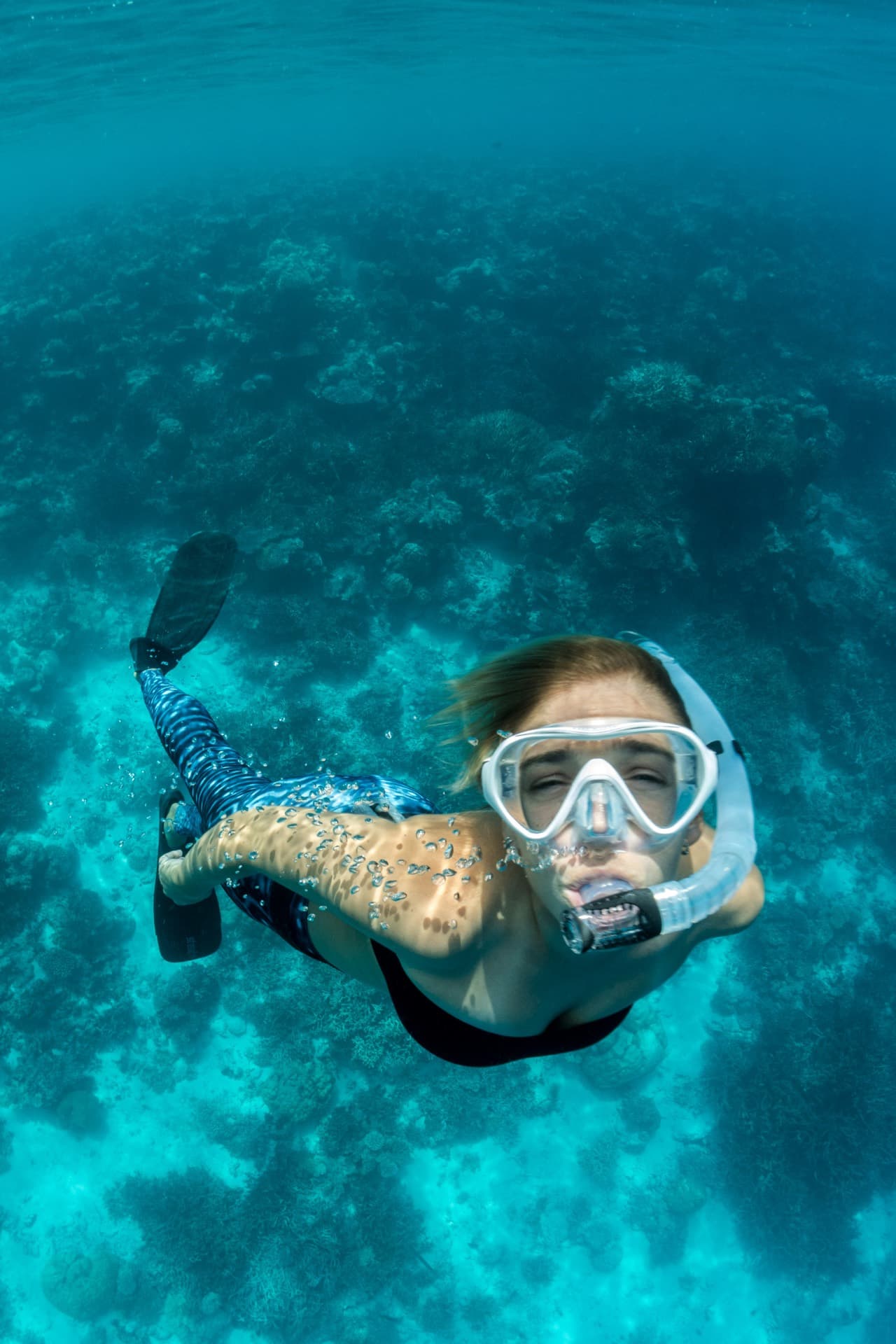 Persona haciendo snorkel sobre un arrecife de agua clara